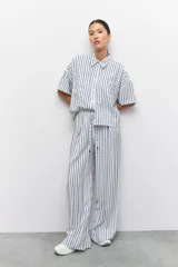 Pantalón largo azul con rayas verticales blancas, de corte amplio, con cintura elastizada y cordón ajustable.