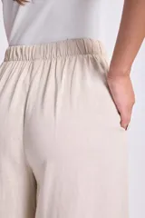 Pantalón de lino color beige, de corte palazzo, con cintura elastizada y cordón ajustable.