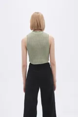 Chaleco verde pálido de punto con cuello alto y diseño trenzado.