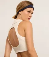 Top deportivo blanco hueso de microfibra, sin estampa, con cuello polo, escote V y recorte abierto en la espalda.