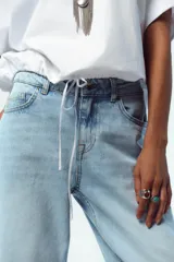 Camiseta blanca de algodón con cuello redondo, mangas cortas y bajo asimétrico ajustable con lazadas.