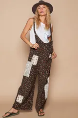 Mono largo de algodón con estampado floral en tonos marrones y detalles de patchwork con telas estampadas en blanco y negro. Tiene tirantes finos, corte holgado y bolsillos laterales.