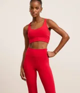 Top deportivo alargado color rojo, confeccionado en microfibra con escote en U, tiras finas cruzadas en la espalda y cintura ancha. Incluye copas removibles.