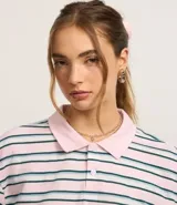 Remera de media malla con cuello polo, manga corta y estampado de rayas horizontales en tonos rosa, blanco y azul.