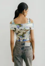 Top de jersey con estampado abstracto en tonos celeste, azul y negro. Diseño con hombros descubiertos y corte cruzado en el frente.