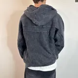 Campera con capucha de algodón color gris oscuro con efecto lavado y cierre frontal. Tiene bolsillos laterales y puños ajustados.