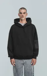 Hoodie negro oversize de rústico 100% algodón con capucha forrada y bolsillo tipo bomber con cierre en la manga.