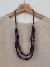 Collar de doble vuelta con cuentas de acrílico de diferentes formas y colores, engarzadas en cordón de gamuza marrón con cierre de mosquetón plateado y cadena de alargue.