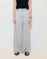 Pantalón gris de lino, de pierna ancha con pinzas, tiro medio, bolsillos laterales inclinados, raya de aplomo y bolsillos traseros ojal y con tapa. Tiene cierre y botón en la cartera y cintura interna prearmada.