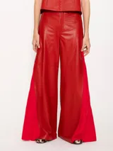 Pantalón de cuero vacuno negro, de silueta amplia con recortes diagonales en delantero y espalda. Tiene un complemento de lino al tono aplicado en los laterales.