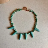 Collar corto con cuentas de piedra turquesa irregulares y colgantes en forma de colmillo.