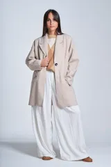 Tapado gris oscuro de corte oversize, con solapa clásica, hombros caídos, cierre con un botón central y bolsillos laterales funcionales.