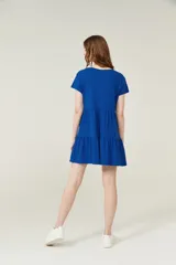 Vestido corto lila con cuello en V y mangas cortas. Tiene corte holgado y dos volados en la falda.