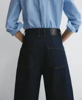Pantalón de denim azul oscuro, corte barrel fit, con triple pespunte a contraste en interior y exterior de la pierna, cierre con botón metálico, trabillas y cinco bolsillos.