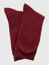 Calcetín de tejido grueso color bordó, largo medio, con puño suave acanalado y etiqueta con las iniciales "HP" en el borde superior.