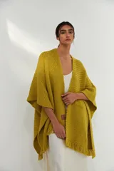 Ruana tejida color verde pistacho con flecos en el borde inferior y parche de cuero en la parte inferior.