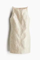 Vestido corto sin mangas en tejido brocado color crema con hilos brillantes en la trama. Modelo ajustado con breteles finos y escote recto alto. Cierre oculto en la parte de atrás. Forrado.