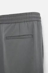 Pantalón color arena de corte recto, confeccionado en tejido elástico. Cuenta con cintura elástica ajustable con cordón, bolsillos laterales y bolsillos de vivo en la parte trasera.