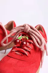 Zapatillas bajas marrones de gamuza con cordones y detalle de aplique de fresa en los cordones.