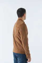 Campera de gamuza color beige con cuello mao, cierre frontal con cremallera, bolsillos laterales con cierre y puños con botón.