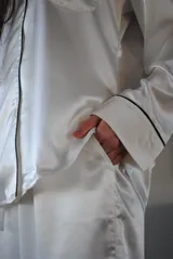 Pijama de satén celeste con vivos en contraste. Incluye camisa de manga larga con botones y pantalón recto con elástico y lazo en la cintura.