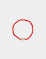 Pulsera elástica de mostacillas rojas con dije de corazón dorado.
