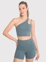 Top deportivo asimétrico de un hombro color gris, con abertura y tirante fino. Cuenta con sujetador integrado y almohadillas removibles.