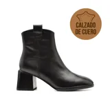 Bota de cuero negra con caña baja, punta fina y taco geométrico.