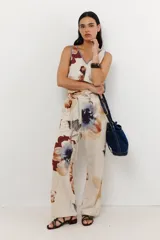 Pantalón de lino color celeste con estampado de flores grandes en tonos marrones, azules y rojos. El pantalón es de corte ancho y tiene cintura alta con cordón ajustable.