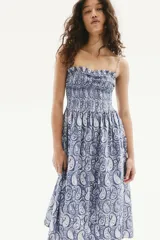 Vestido midi de algodón con estampado paisley en tonos azules y blancos. Tiene breteles finos ajustables y escote recto con frunces. El cuerpo es fruncido con costura elástica en el busto y la falda tiene un leve vuelo.