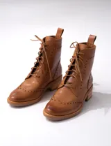 Bota corta de cuero color marrón claro, con cordones y detalles de perforaciones. Tiene un pequeño taco de madera.