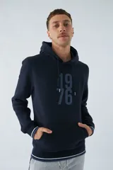 Buzo canguro color marrón con capucha ajustable, bolsillo canguro, fit regular, arte estampado en relieve y logo en goma.