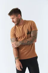 Remera color caramelo de corte clásico, con cuello redondo y manga corta. Estampa pequeña en el pecho con el dibujo de un edificio y la inscripción "BROOKSFIELD".