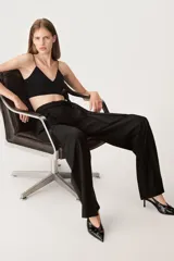 Pantalón negro de tiro alto confeccionado en mezcla de lana, con trabillas en la cintura, bolsillos laterales y falsos bolsillos de vivo en la espalda. Incluye cinturón de lazo en el mismo tejido y cierre frontal con cremallera, botón interior y ganchos metálicos.