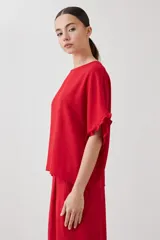 Blusa roja de manga corta con volados en los puños y cuello redondo.