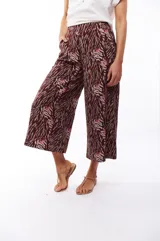 Pantalón capri negro con estampado abstracto en tonos beige, gris y marrón.