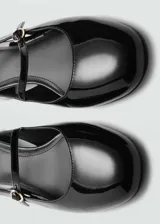 Zapato destalonado color beige con efecto charol, taco bloque de 5 cm, punta redonda y tira con hebilla.
