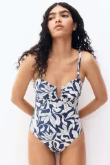 Traje de baño enterizo con estampado floral en azul y blanco, con breteles ajustables extraíbles, alambre en forma de U en la parte central del busto, copas con relleno extraíble, piernas de corte alto y cobertura media en la parte de atrás.
