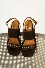 Sandalias de tacón de madera con tiras de gamuza marrón y detalles de tachas metálicas.