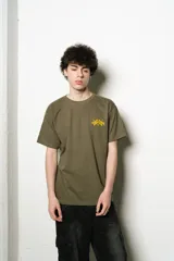 Remera verde oliva de corte regular fit, confeccionada en jersey de algodón. Presenta un pequeño logo bordado en el pecho y un estampado grande con el nombre de la marca en la espalda, ambos en color amarillo.