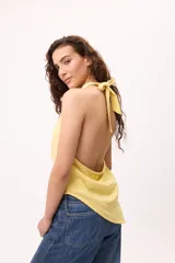 Top amarillo de algodón con cuello halter, espalda descubierta y terminación irregular.