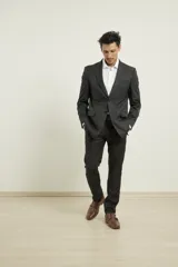 Traje de poliéster negro, corte regular fit, compuesto por saco con solapa de muesca, cierre de dos botones, bolsillos con solapa y pantalón de vestir con bolsillos laterales y traseros.