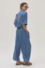 Blusa celeste de denim con cuello camisero, mangas cortas y cierre frontal con botones.