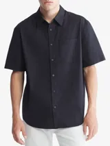 Camisa negra de manga corta confeccionada en algodón. Tiene cuello clásico, cierre frontal con botones, bolsillo de parche en el pecho y corte holgado.