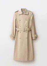 Trench beige de algodón con cuello de solapa, doble botonadura, cinturón con hebilla, trabillas en hombros y mangas largas con trabillas.