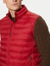 Chaleco rojo Tommy Hilfiger plegable, con cuello chimenea, cierre de cremallera, dos bolsillos laterales con cremallera y logo bordado en el pecho. Confeccionado en tejido de nailon que repele el agua.