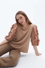 Remera color beige con mangas cortas y volados con borde naranja.