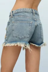 Short de jean celeste con bordados de canutillos y lentejuelas beige con formas asimétricas. Tiene roturas y terminación desflecada.