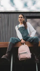 Mochila de nylon color rosa con detalles en símil cuero en el bolsillo frontal. Tiene asa de mano, correas regulables, bolsillo interno con cierre, bolsillo interno abierto con división y bolsillo trasero vertical con cierre.