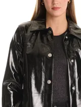 Chaqueta larga tipo trench de charol negro con acabado brillante e impermeable. Presenta cuello con solapa, cierre frontal con botones metálicos plateados y bolsillos laterales. Su diseño es de corte recto y estructura rígida.